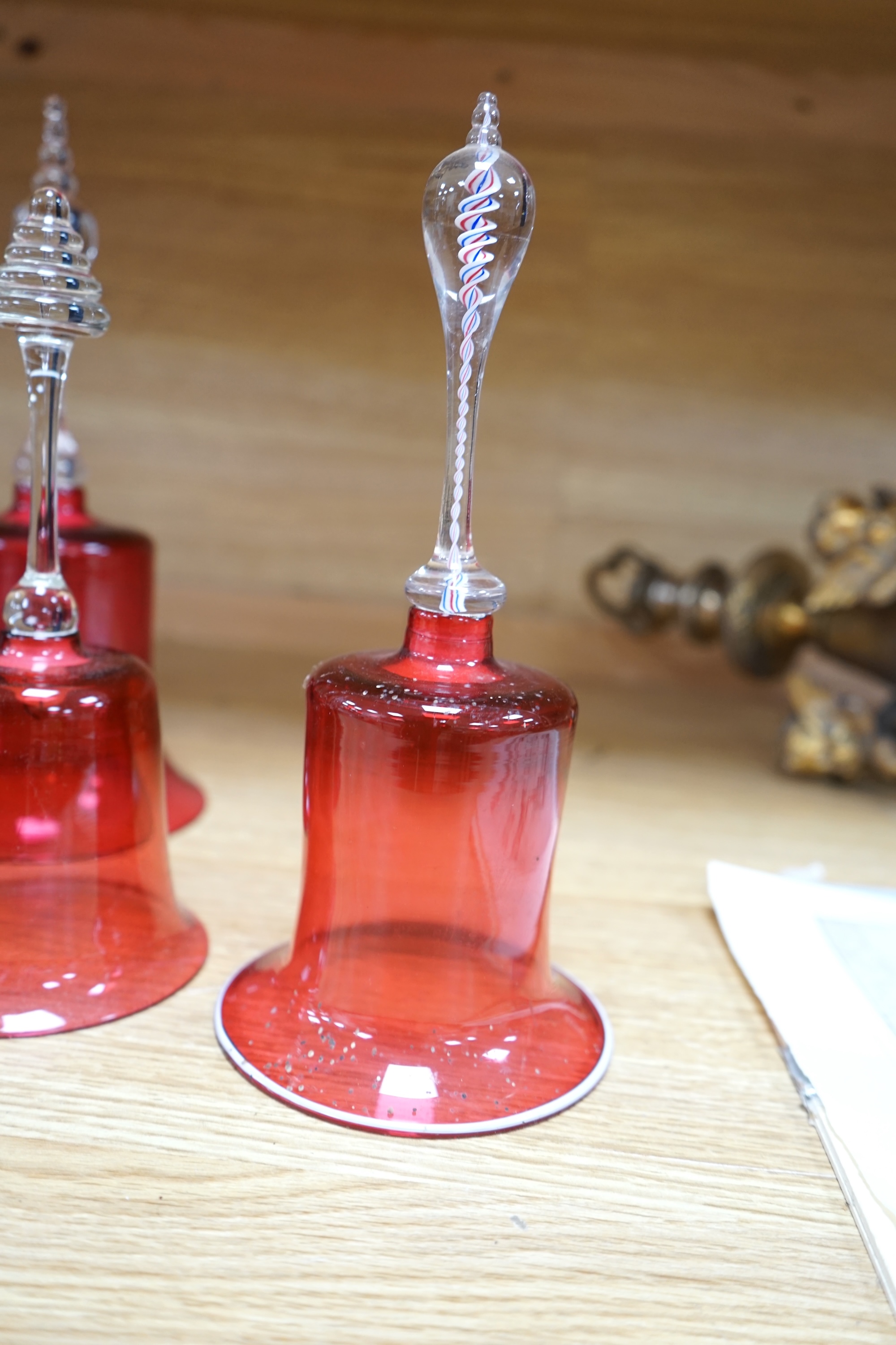 Seven 19th century cranberry glass hand bells, various sizes, largest 30.5cm high. Condition - fair